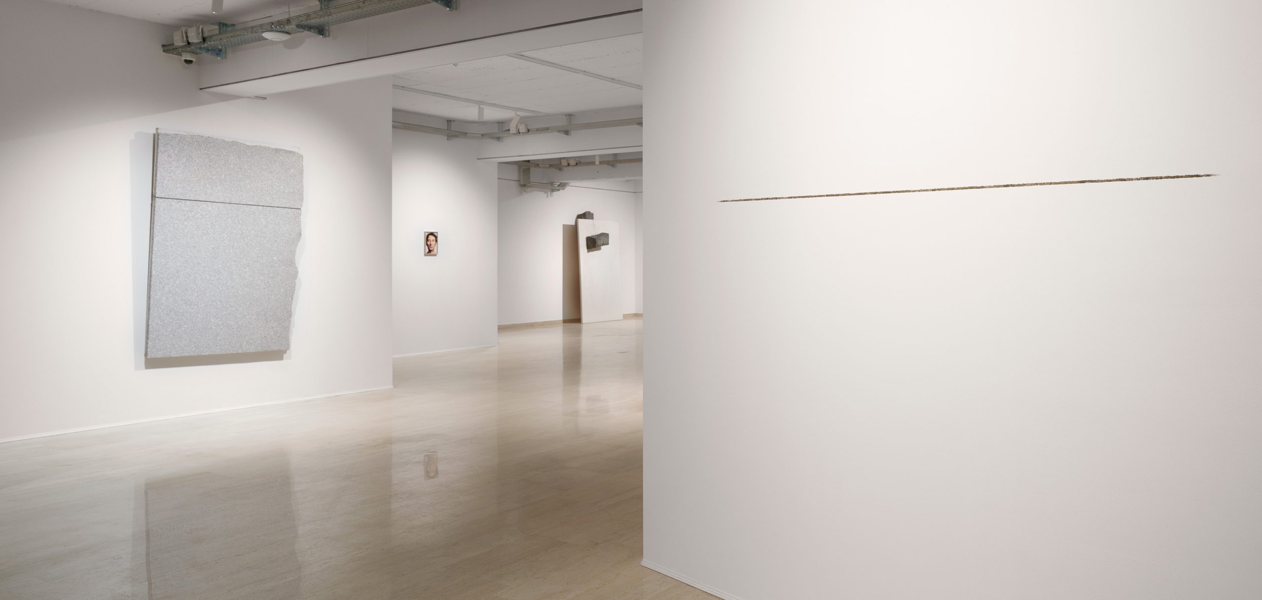 Installation view of Giovanni Anselmo’s exhibition at Repetto Gallery in Lugano, with artworks displayed throughout the white gallery space.