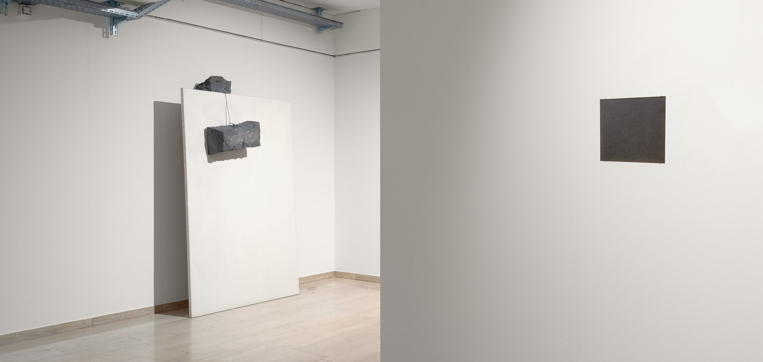 Installation view of Giovanni Anselmo’s exhibition at Repetto Gallery in Lugano, with artworks displayed throughout the white gallery space.